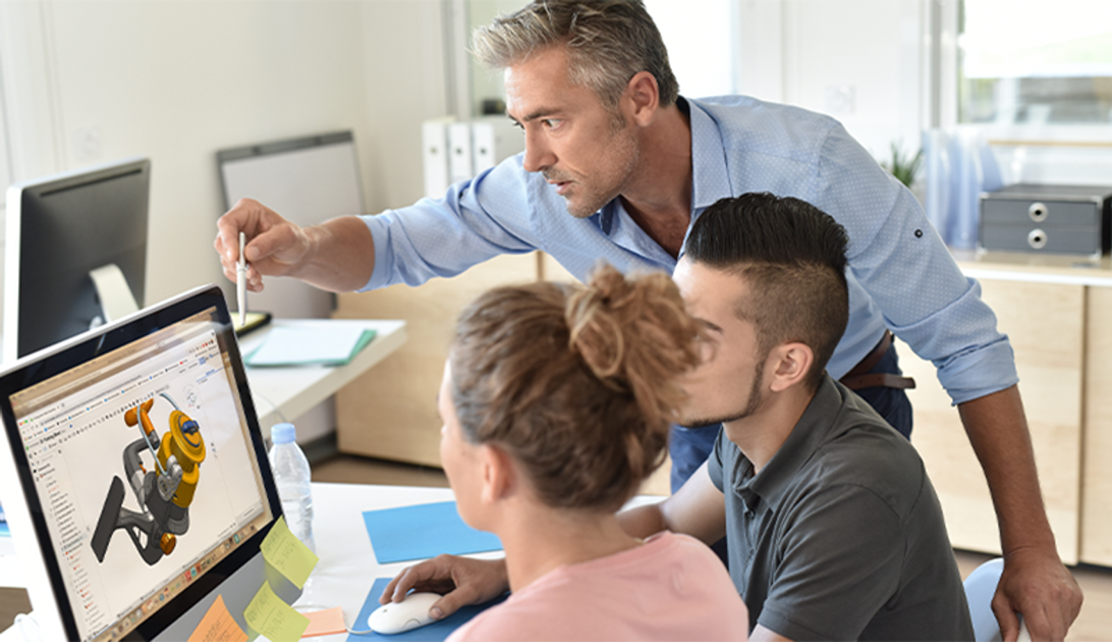 a teacher helping two students at a computer with an Onshape model displayed